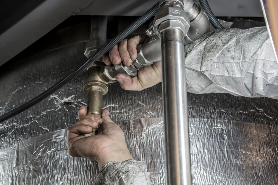 Plumber's hands installing steel pipes during an emergency plumbing repair in Corona, CA