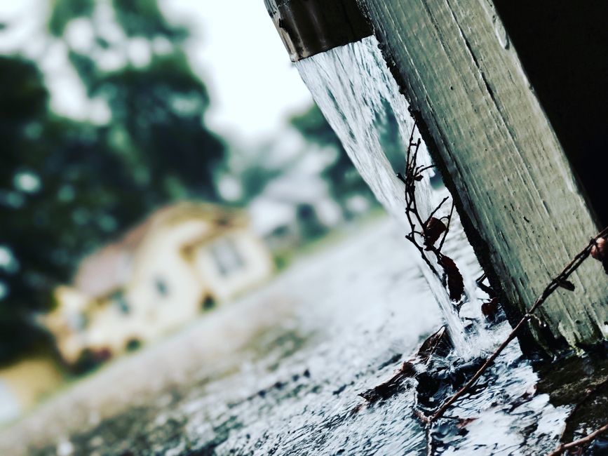 Rainwater pouring from a home gutter during a storm, illustrating why plumbing maintenance matters before Inland Empire rainy season