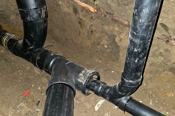New black ABS drain line fittings installed underground