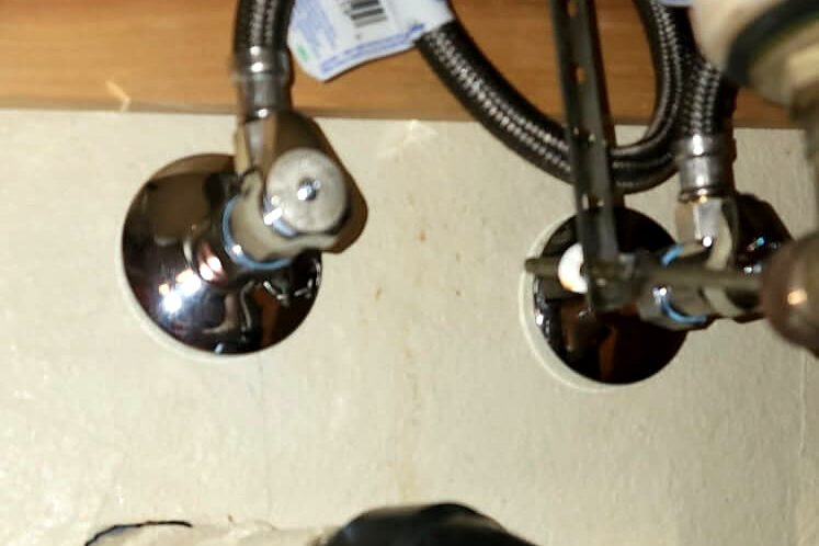 New chrome angle stop valves and drain trap under a sink