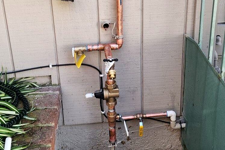 New copper water service line with shutoff valve on a home's exterior wall