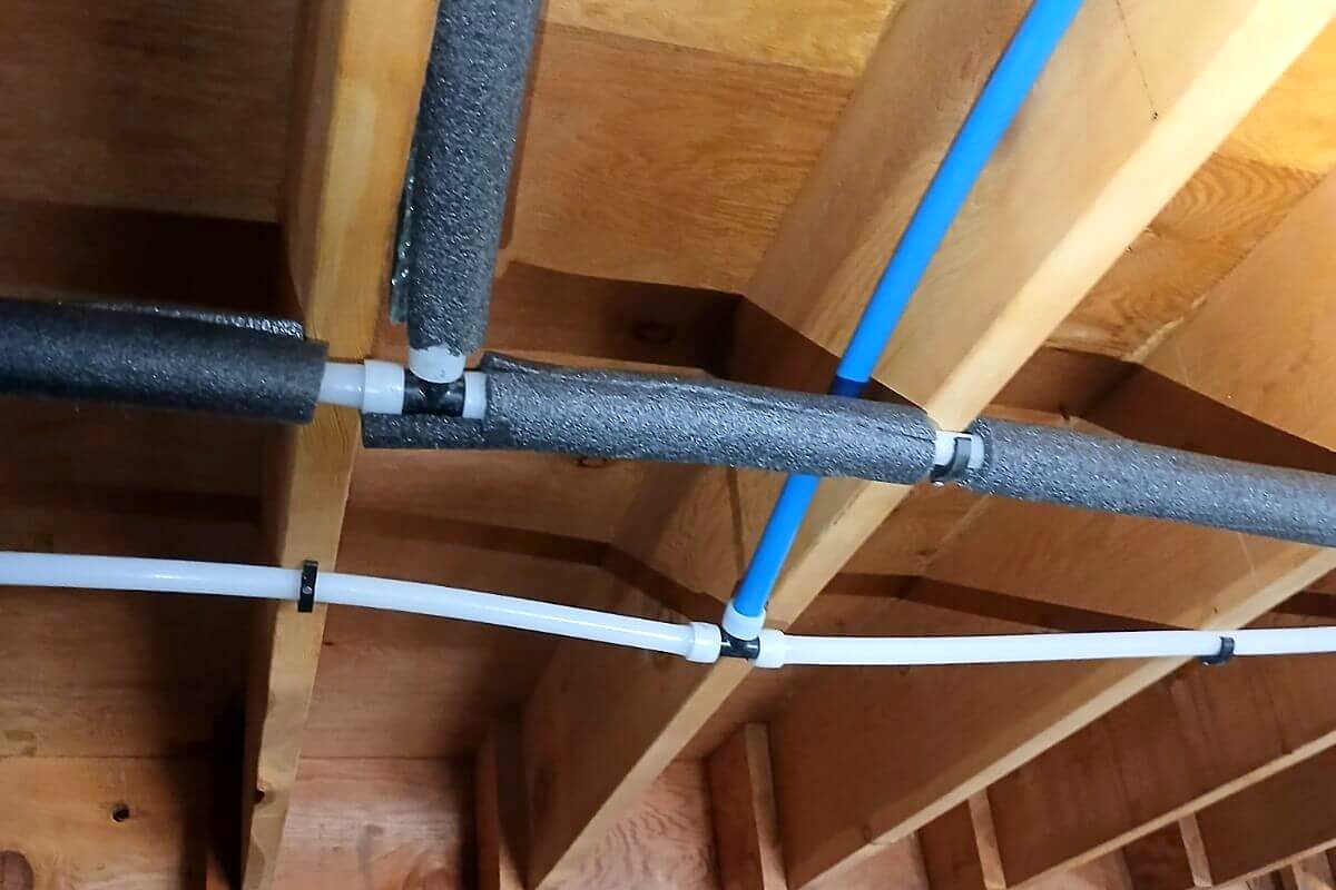 New PEX water lines run along floor joists in a crawl space during a repipe