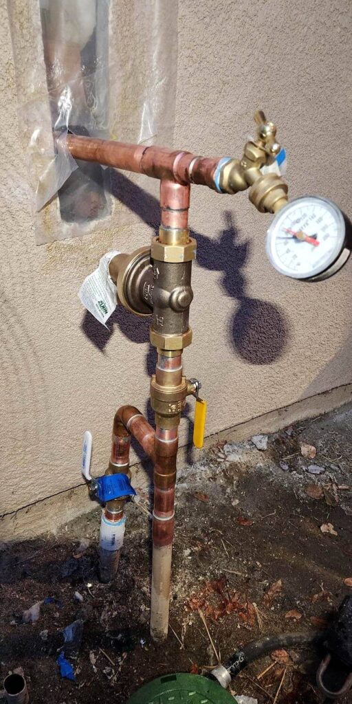 Newly installed pressure reducing valve with gauge and hose bib on copper water line