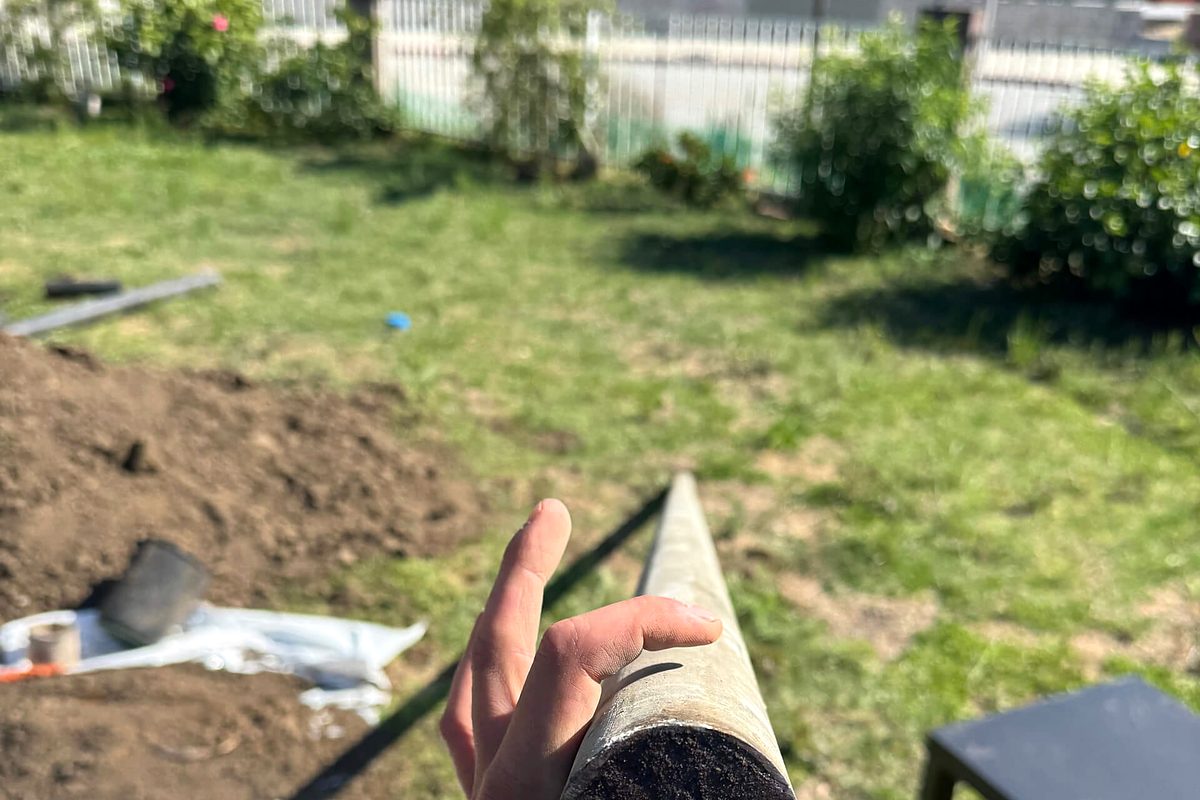 Plumber holding a section of new sewer pipe on a residential job site