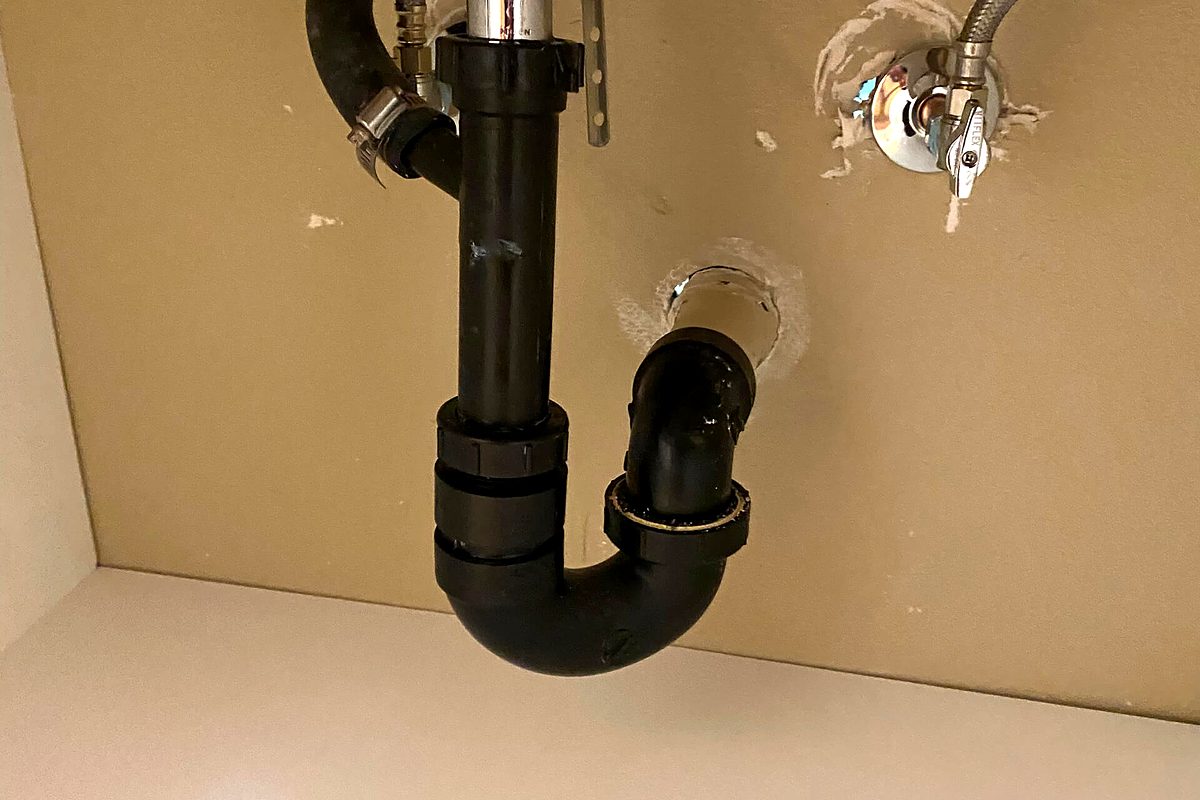 New P-trap and angle stop valves installed under a bathroom sink