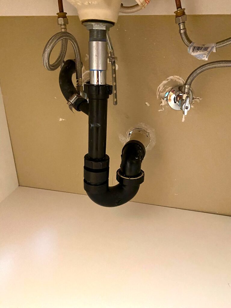 New P-trap and angle stop valves installed under a bathroom sink